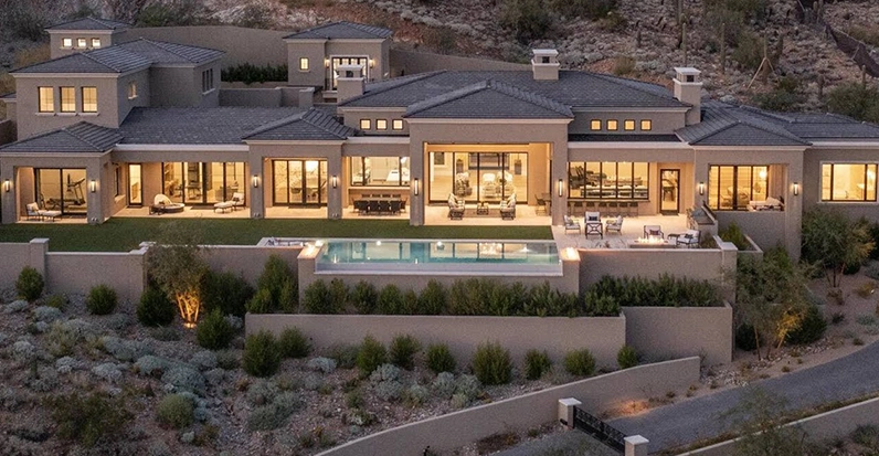 Luxury hillside home with large windows, pool, and landscaped garden.