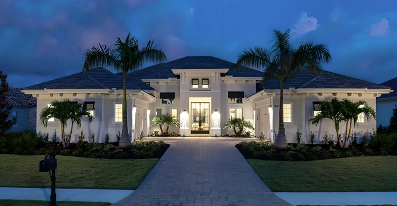Luxury home with palm trees and lit windows at twilight.