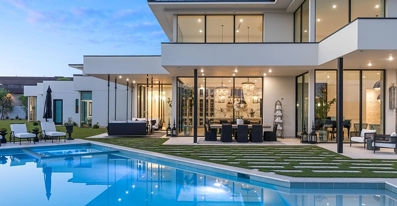 Modern luxury home with large pool and outdoor seating area.