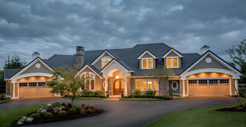 Luxury home exterior with well-manicured lawn and dramatic evening lighting.