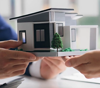 Hands holding a miniature model of a modern house.